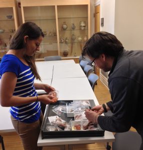 Archaeology graduate students Robyn LeBlanc and Daniel Schindler shift through a tray of pottery samples.
