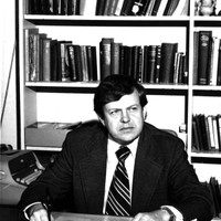 George A. Kennedy sits in front of a bookcase. 