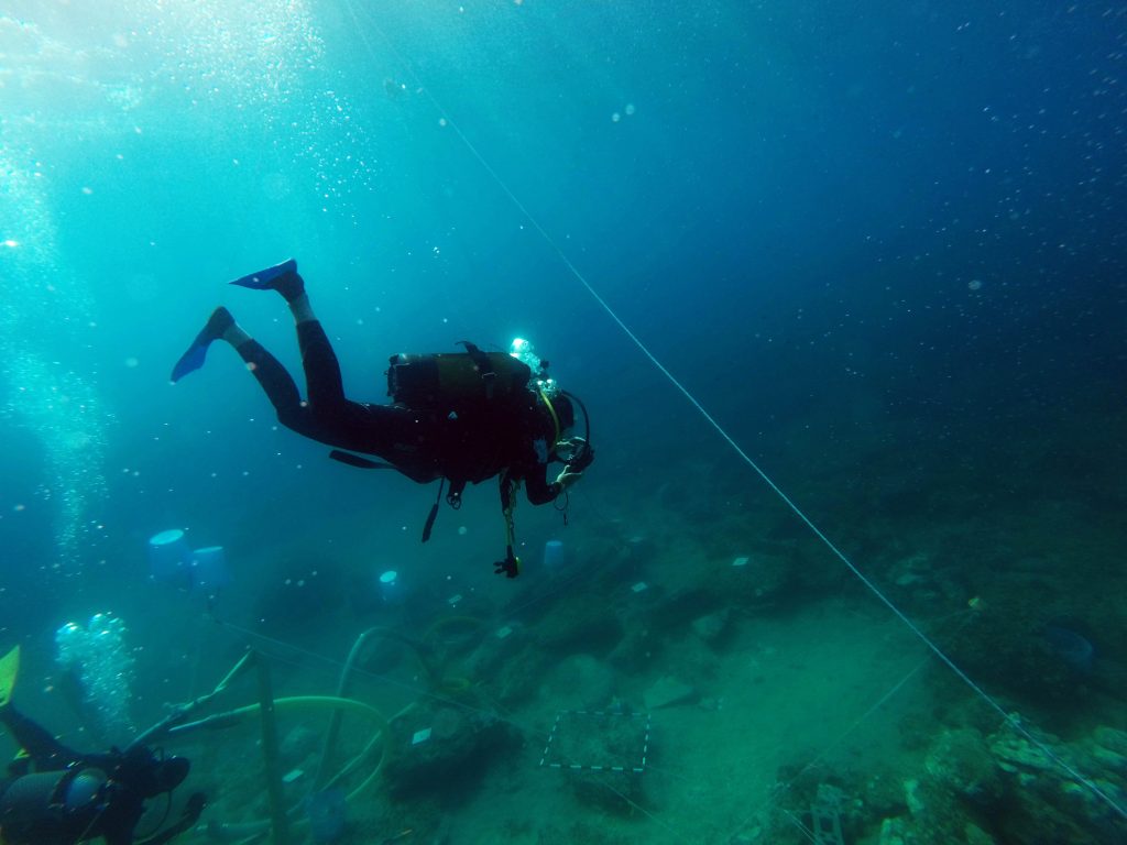 Justin Leiwanger underwater and in a full scuba suit, excavating the Marzamemi Church Wreck.